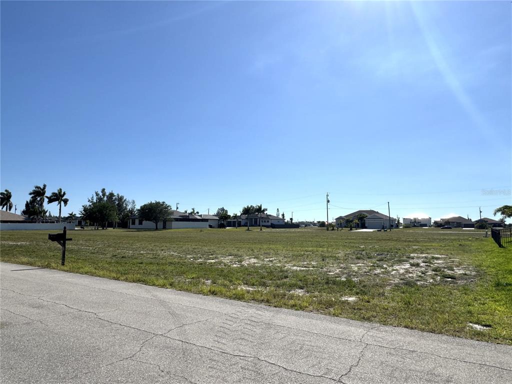 A vacant, grassy residential lot is viewed from an adjacent paved street — 3436 NW 45TH AVENUE, CAPE CORAL, FL