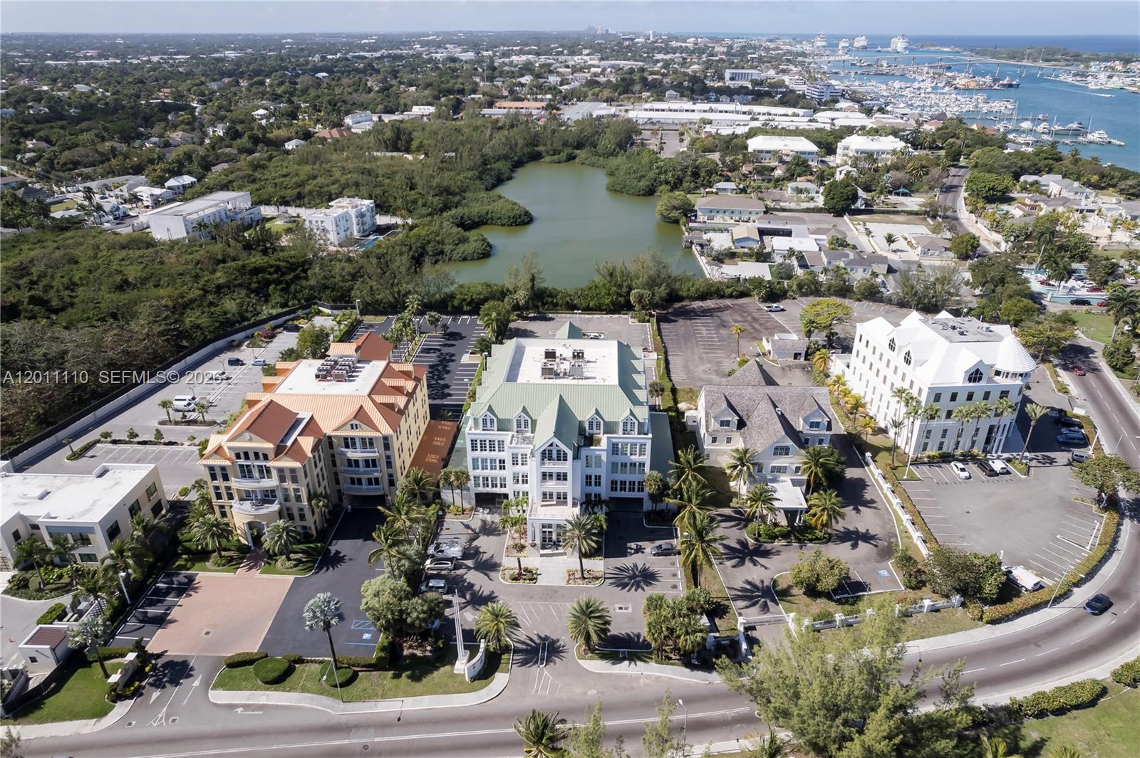An aerial view shows three multi-story office buildings with parking lots near a small lake — 9 E Bay Street, 00000, FL