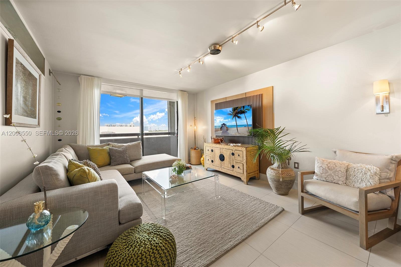 A living room features a sectional sofa, glass coffee table, media console, and balcony access — 1775 Washington Ave # 8F, Miami Beach FL 33139, MIAMI BEACH, FL