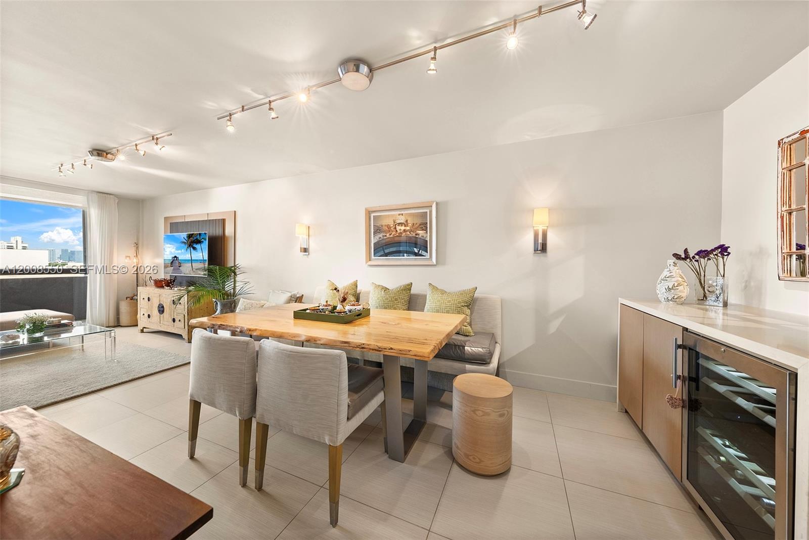 A dining area features a wooden table with chairs and a bench on tile flooring — 1775 Washington Ave # 8F, Miami Beach FL 33139, MIAMI BEACH, FL