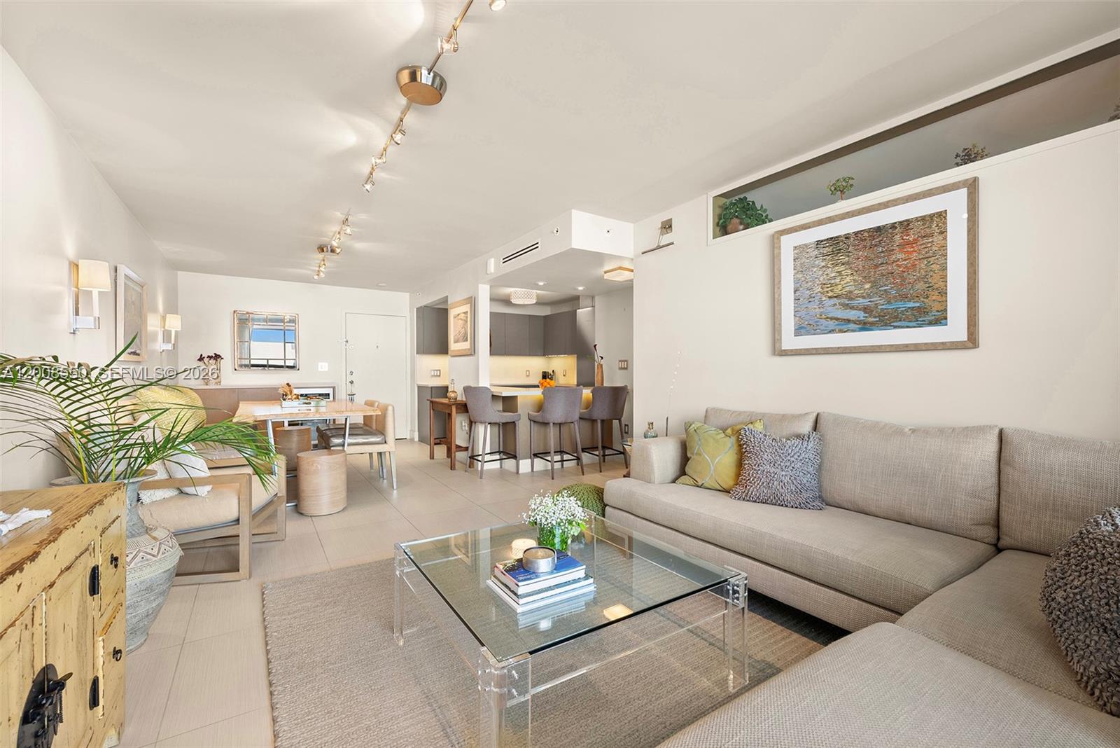 A modern living room features a sectional sofa, glass coffee table, and open kitchen area — 1775 Washington Ave # 8F, Miami Beach FL 33139, MIAMI BEACH, FL