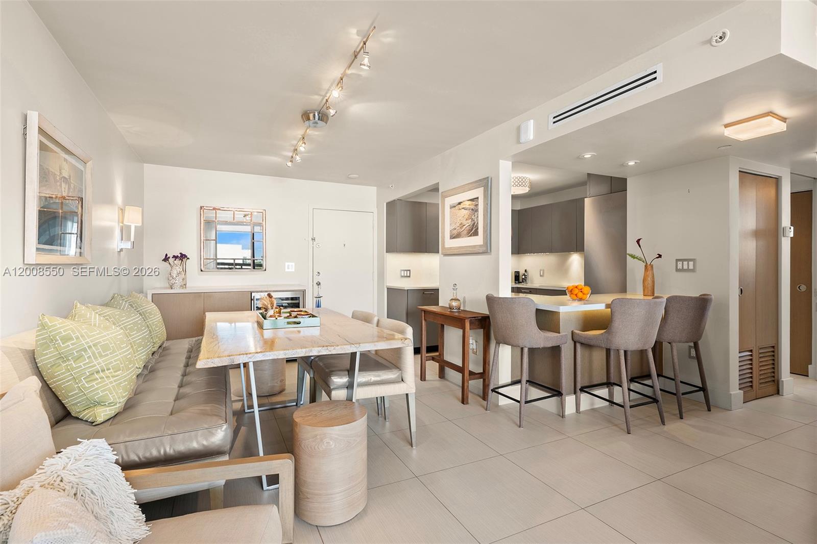 This dining and kitchen area features a long bench seat, a wooden table, and barstools — 1775 Washington Ave # 8F, Miami Beach FL 33139, MIAMI BEACH, FL