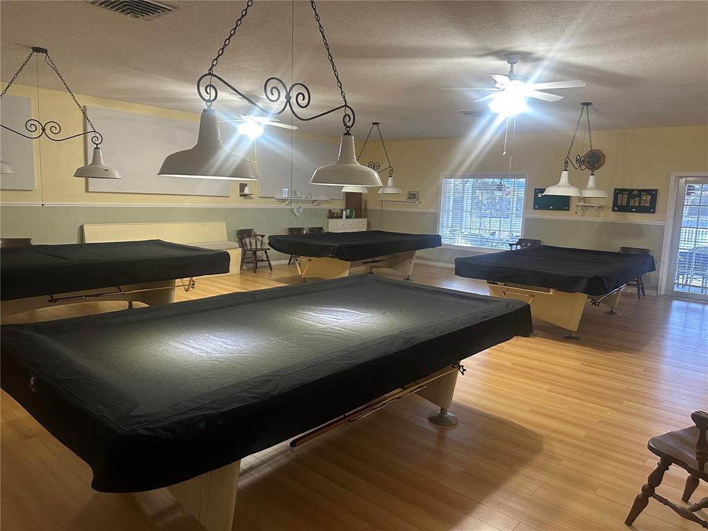A room with light wood flooring contains four pool tables covered in black fabric — 5621 SUNFLOWER ROAD, VENICE, FL