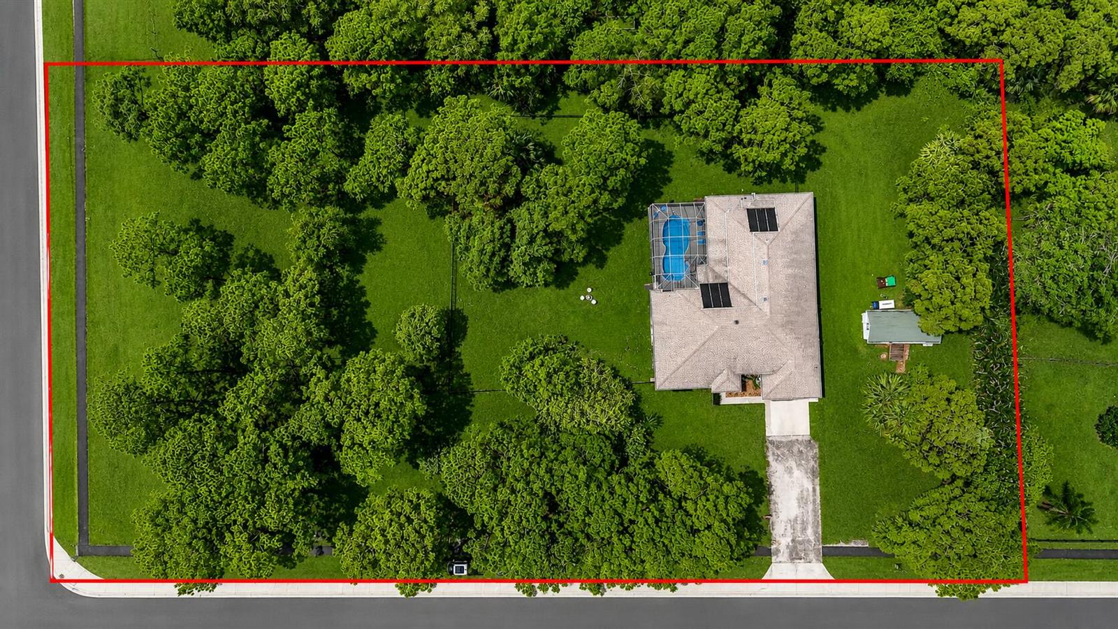 An aerial view shows a house with a pool and a large yard with trees — 16074 66th Court N, FL 33470, FL