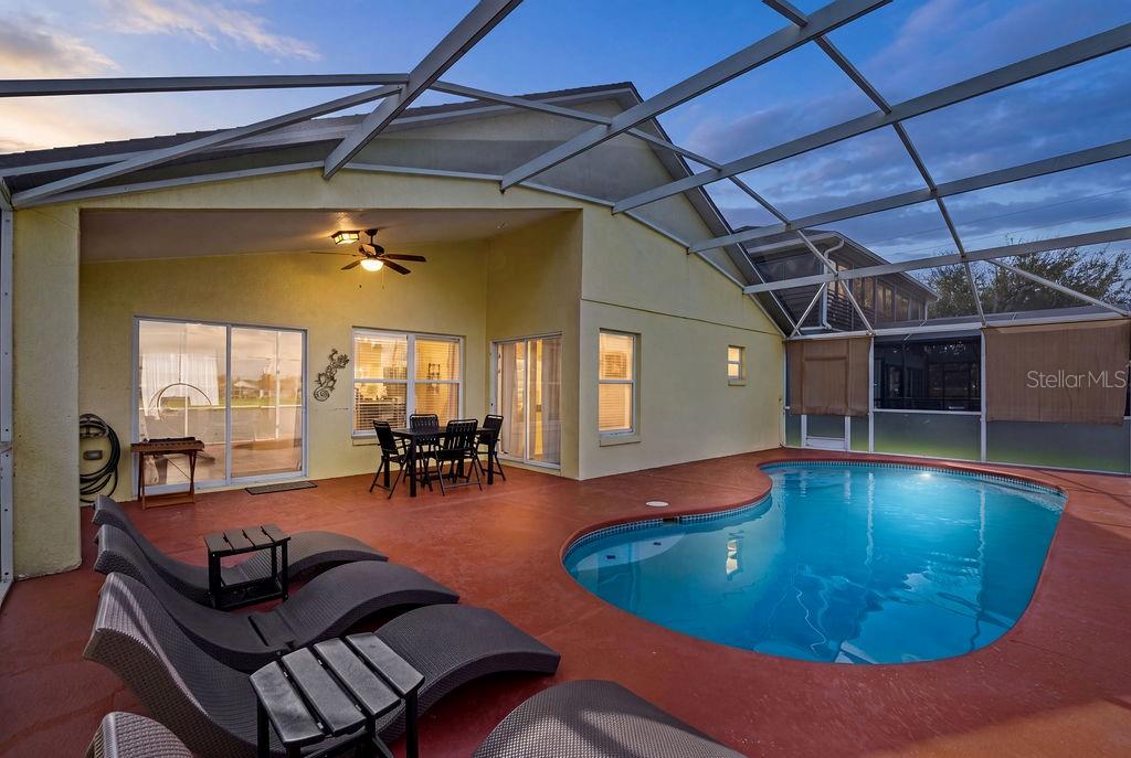 A covered patio features a swimming pool, lounge chairs, and a dining set — 5134 VIOLET LANE, KISSIMMEE, FL