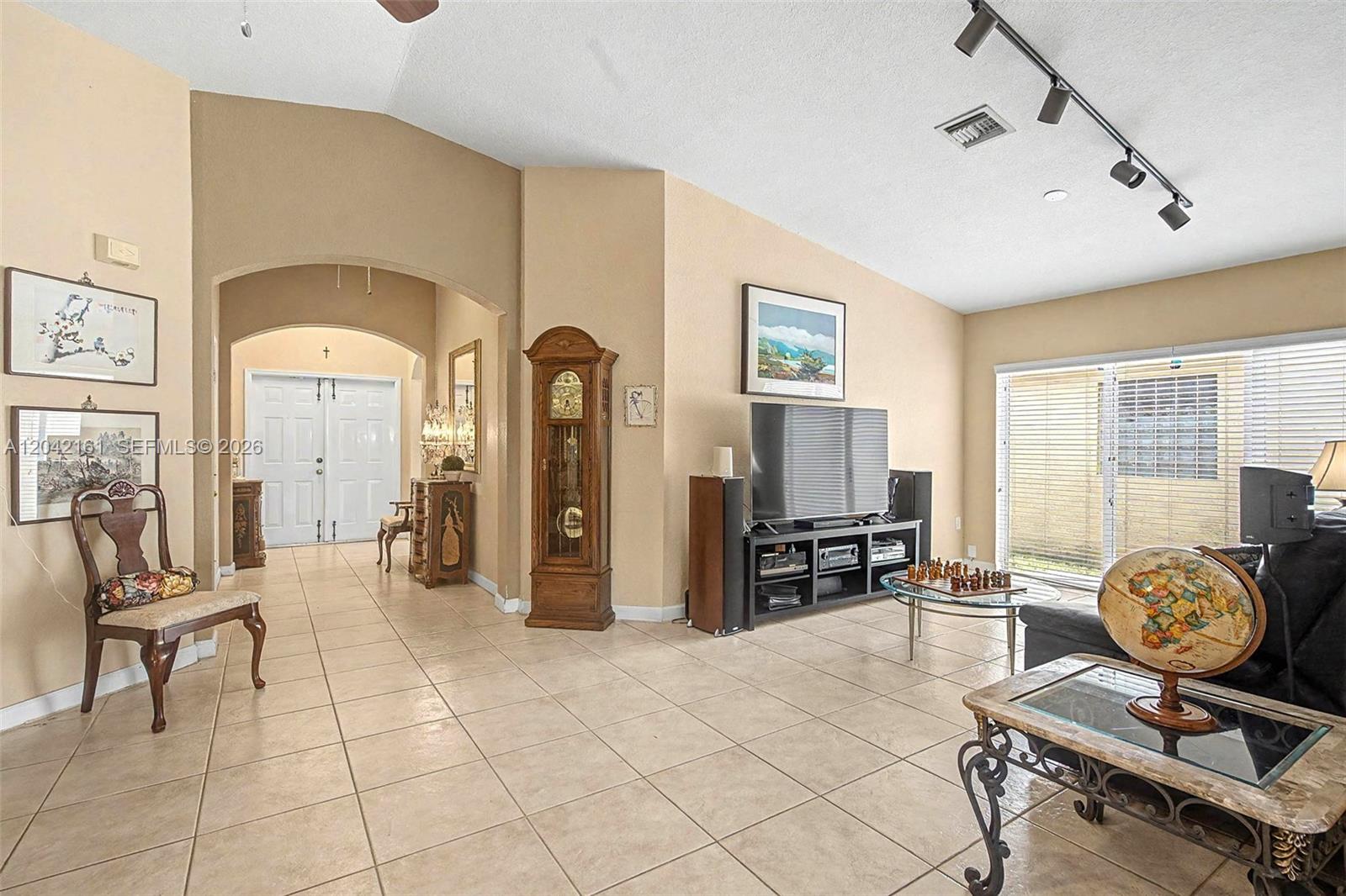A living room features tile flooring, a grandfather clock, a television, and a dining area — 14033 SW 155th Ct, Miami FL 33196, MIAMI, FL