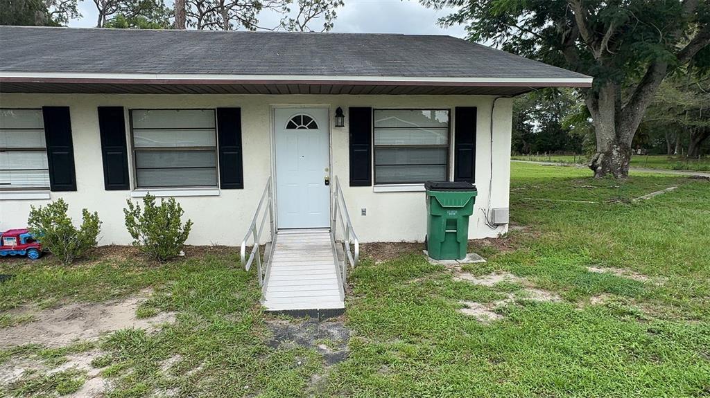 A single-story house exterior features a white front door with a metal wheelchair ramp — 4734 20TH STREET, ZEPHYRHILLS, FL