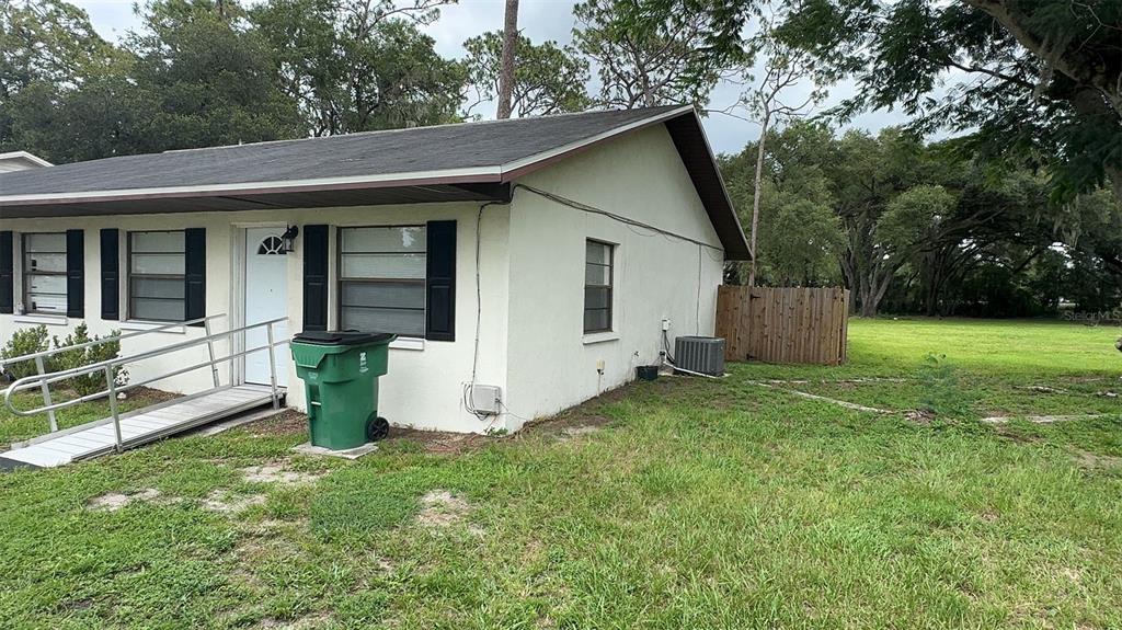 A single-story house with a wheelchair ramp, a green trash bin, and a wooden fence — 4734 20TH STREET, ZEPHYRHILLS, FL