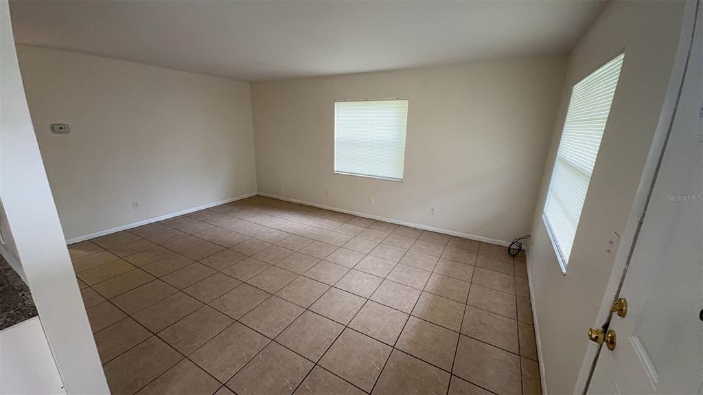 An empty room features light-colored walls, tiled flooring, and two windows with blinds — 4734 20TH STREET, ZEPHYRHILLS, FL