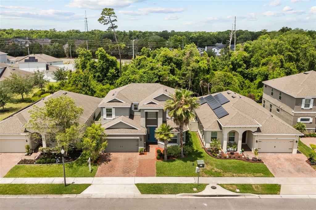 An aerial view shows three suburban houses with paved driveways and green lawns — 1078 CASTLEVECCHIO LOOP, ORLANDO, FL