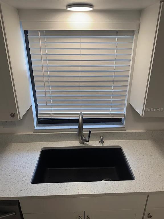 A kitchen sink area features a black undermount sink, white countertops, and a window with blinds — 4845 16TH STREET, ZEPHYRHILLS, FL