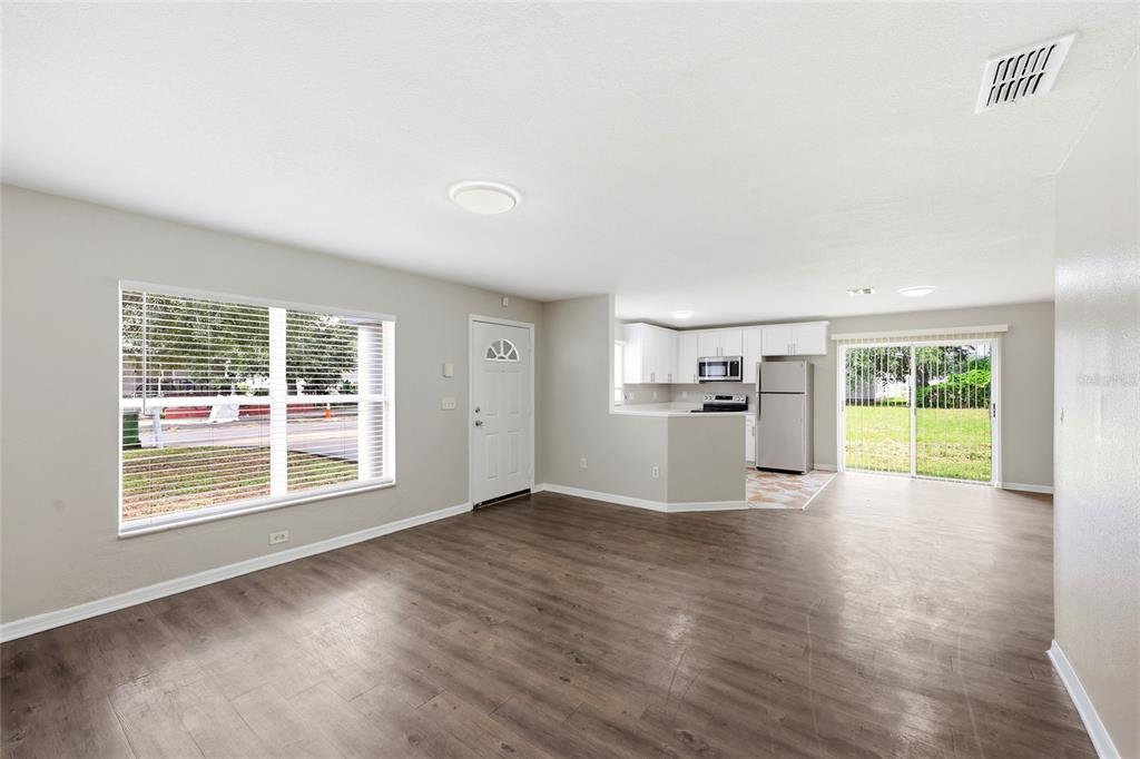 An open-concept living area with wood-look flooring, a kitchen, and a sliding glass door — 2214 E 19TH AVENUE, TAMPA, FL