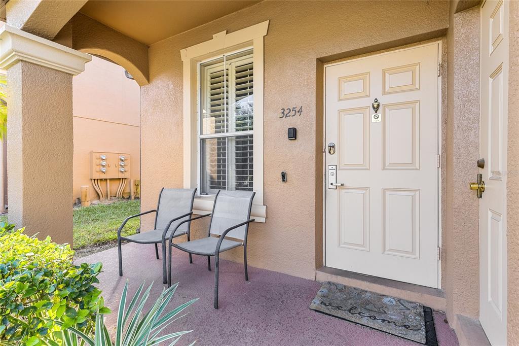 A covered entryway features two chairs, a front door, and a window on a porch — 3254 CALABRIA AVENUE UNIT 3254, DAVENPORT, FL