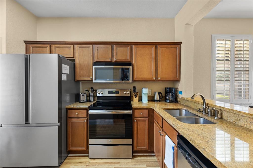 A kitchen features wood cabinets, granite countertops, stainless steel appliances, and a double-basin sink — 3254 CALABRIA AVENUE UNIT 3254, DAVENPORT, FL