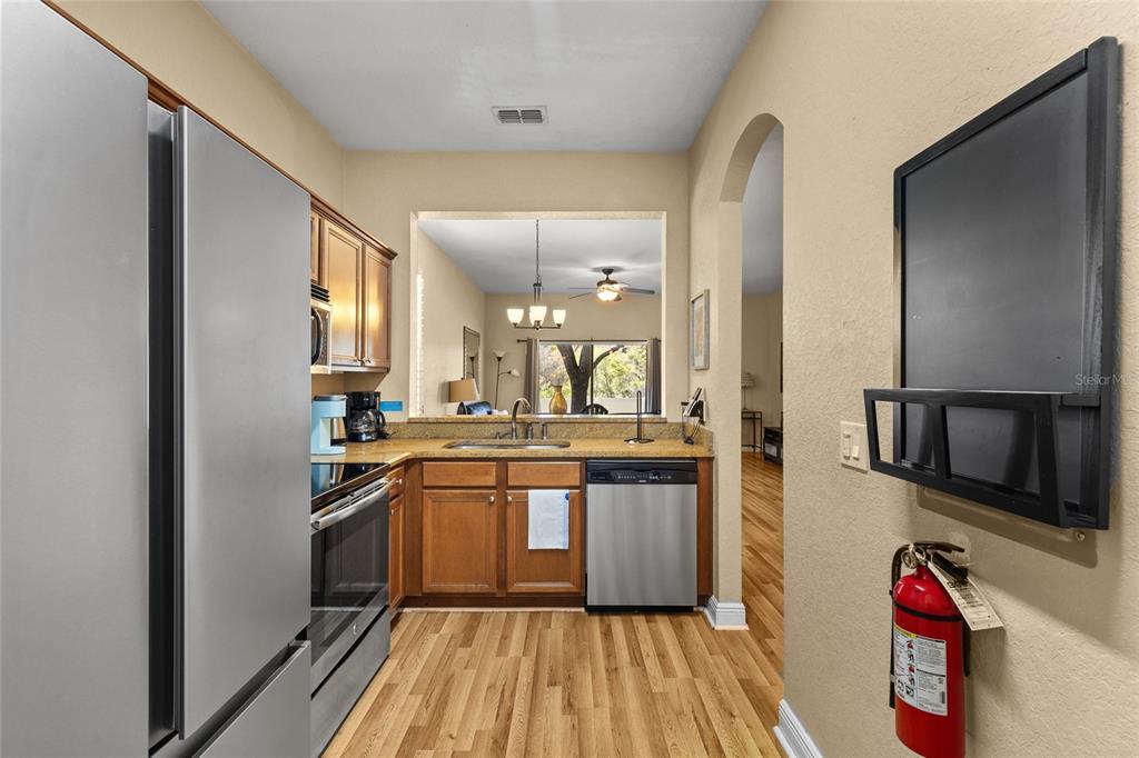 A kitchen features wood cabinets, stainless steel appliances, and a pass-through window to the living area — 3254 CALABRIA AVENUE UNIT 3254, DAVENPORT, FL
