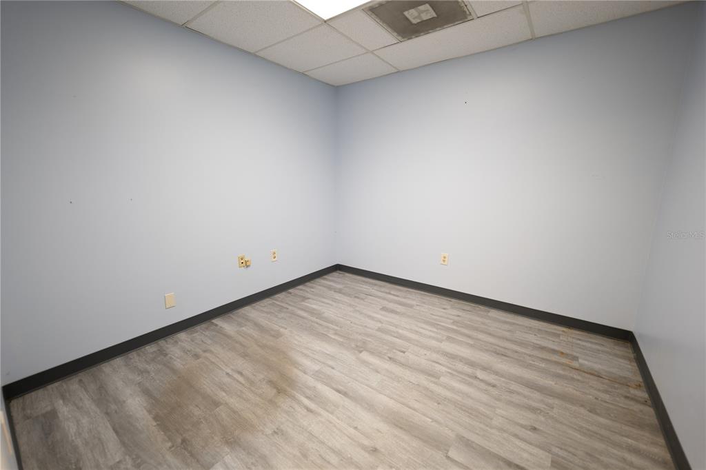 An empty office room with light blue walls, wood-look flooring, and a drop ceiling — 1209 TECH BOULEVARD UNIT 207, TAMPA, FL