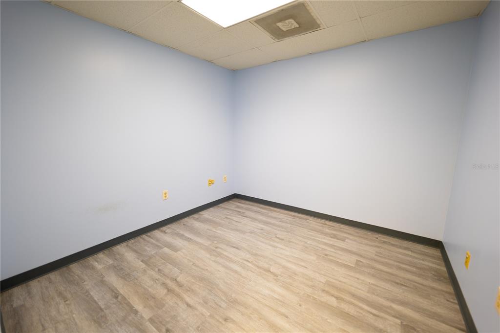An empty office room with light blue walls, wood-look flooring, and a drop ceiling — 1209 TECH BOULEVARD UNIT 207, TAMPA, FL