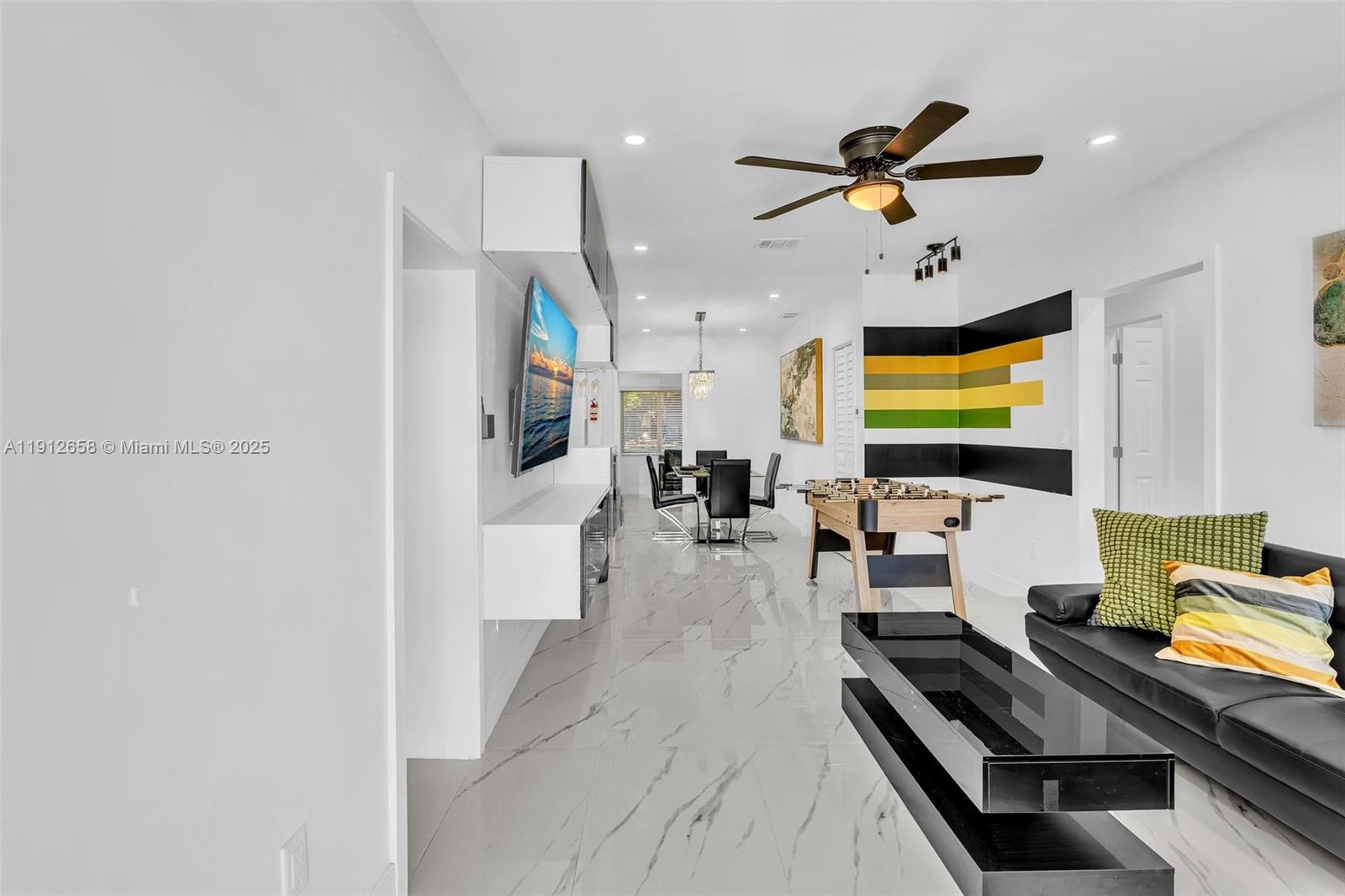 A modern living and dining area features marble floors, a foosball table, and wall art — 797 NW 35th St, Miami FL 33127, MIAMI, FL
