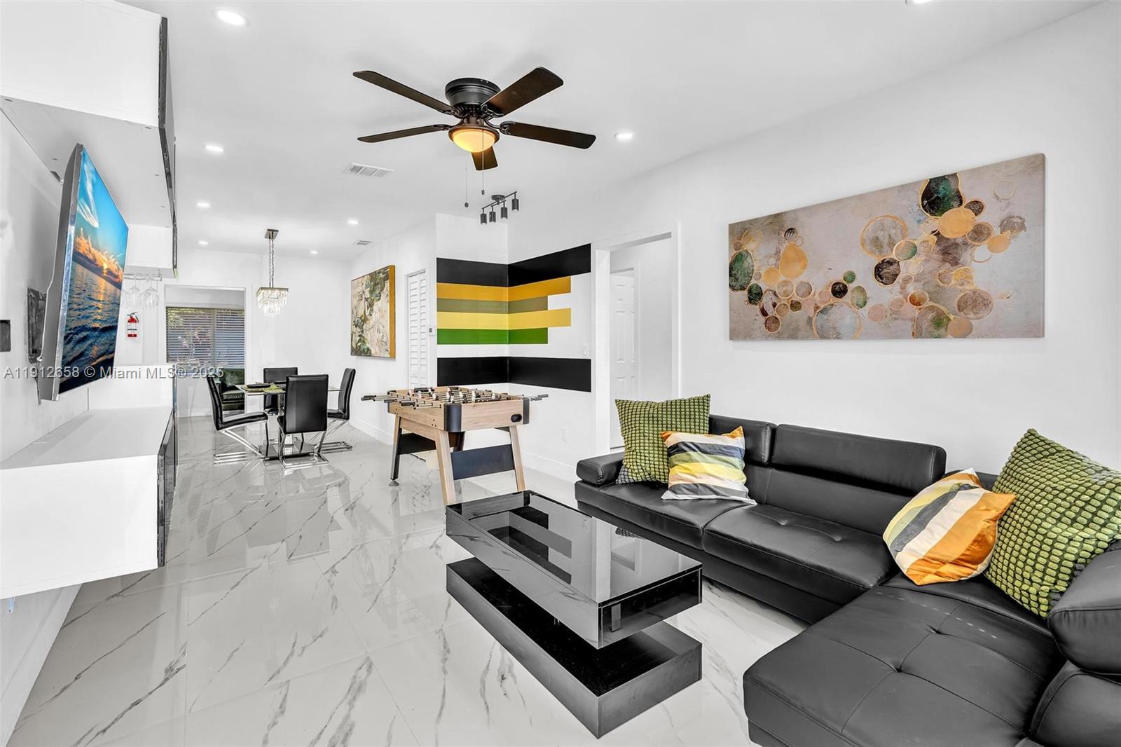 A living room features a black sectional sofa, a foosball table, and white marble flooring — 797 NW 35th St, Miami FL 33127, MIAMI, FL