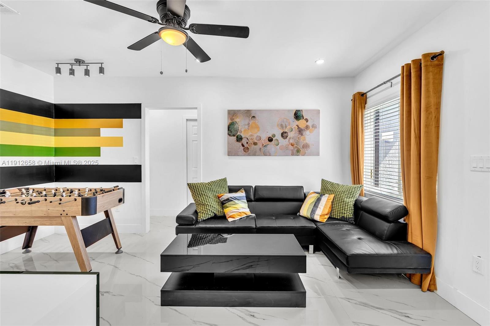 A living room features a black sectional sofa, foosball table, and yellow curtains — 797 NW 35th St, Miami FL 33127, MIAMI, FL