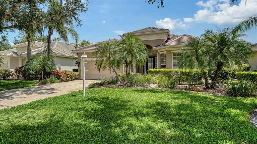 A single-story house with a beige stucco exterior, a tiled roof, and a front lawn — 6909 LENNOX PLACE, BRADENTON, FL