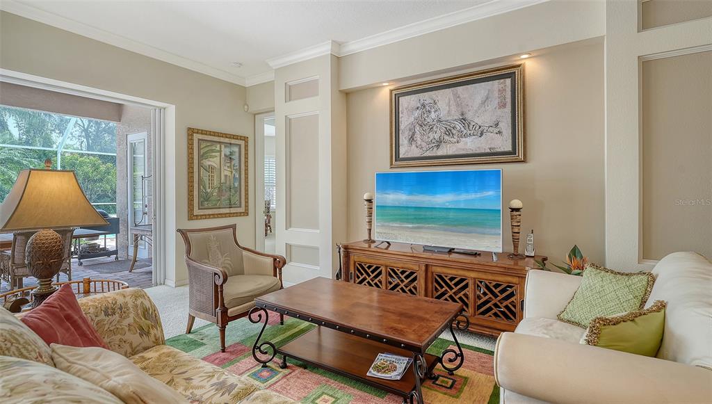 A living room features a television on a wooden console, a coffee table, and seating — 6909 LENNOX PLACE, BRADENTON, FL