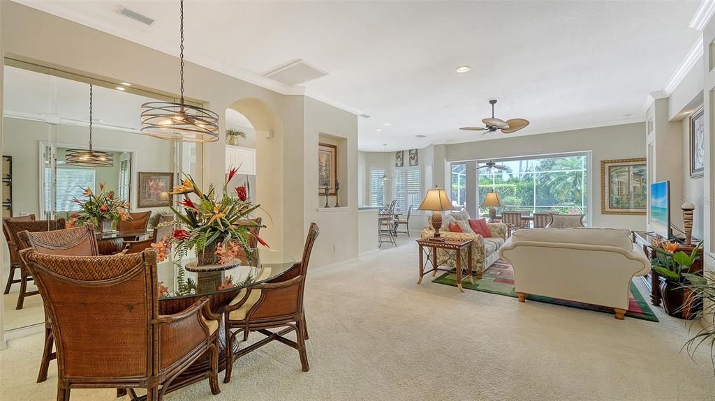 A dining area with a glass table and wicker chairs opens into a spacious living room — 6909 LENNOX PLACE, BRADENTON, FL