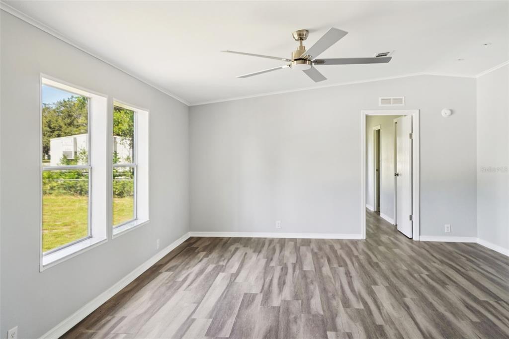 An empty room with light gray walls, wood-look flooring, a ceiling fan, and two windows — 29417 KELLY DRIVE, WESLEY CHAPEL, FL