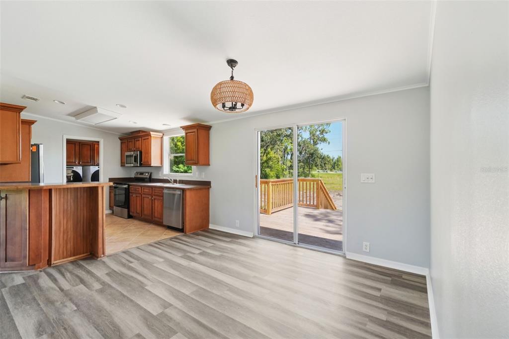 A kitchen with wood cabinets and a dining area featuring sliding glass doors to a deck — 29417 KELLY DRIVE, WESLEY CHAPEL, FL