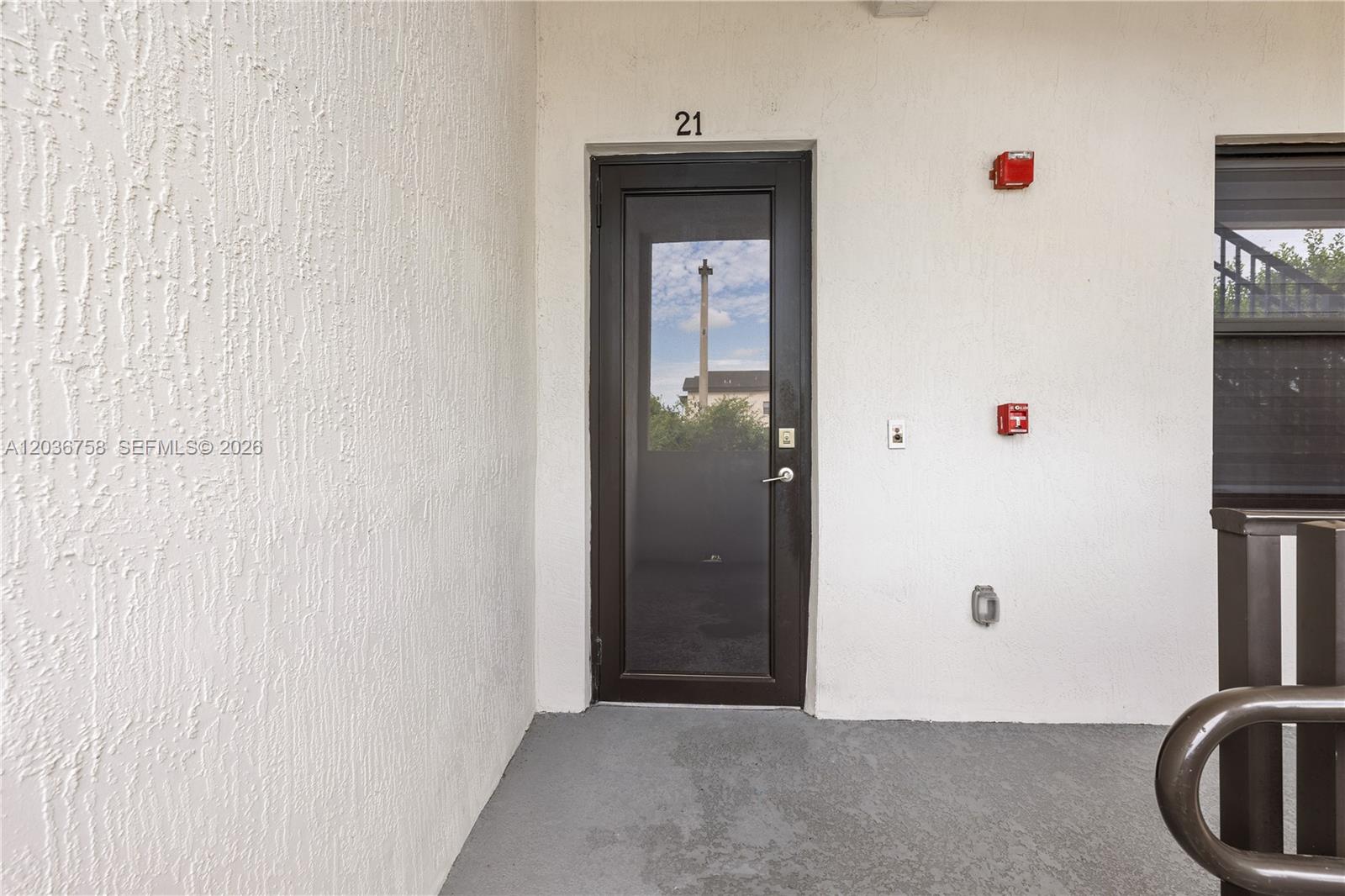 A dark-framed glass door labeled 21 is set into a white textured exterior wall — 7925 NW 104th Ave # 21, Doral FL 33178, DORAL, FL