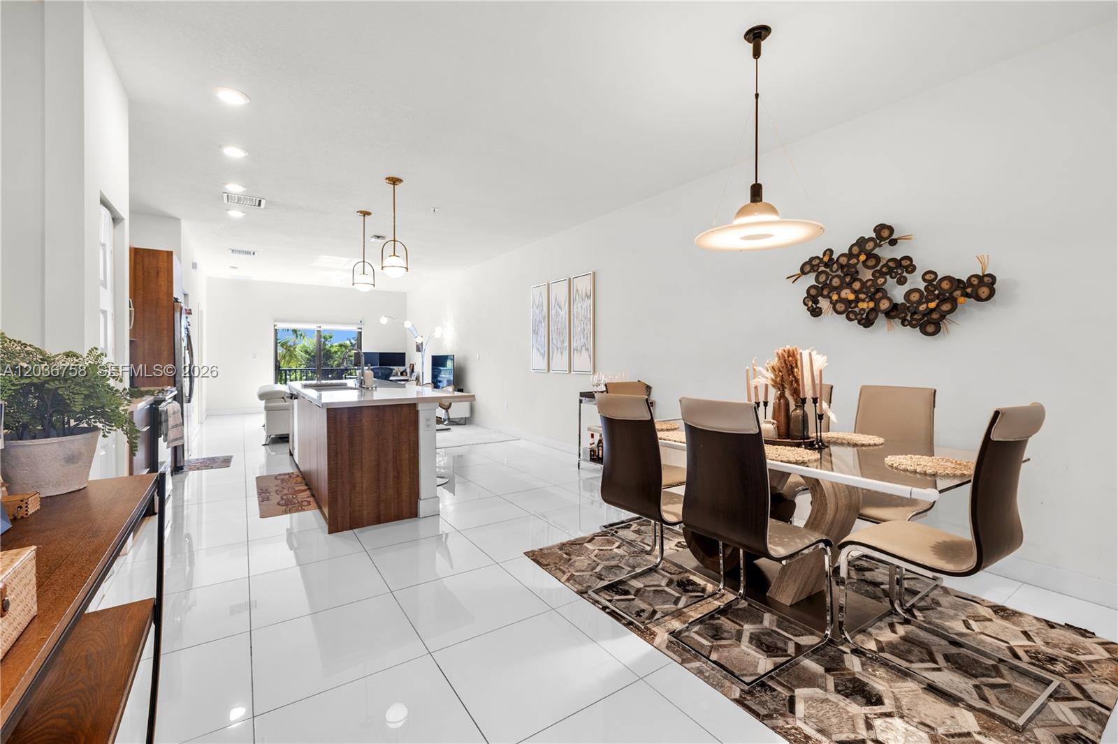 An open-concept dining and kitchen area features white tile floors, modern lighting, and wood cabinetry — 7925 NW 104th Ave # 21, Doral FL 33178, DORAL, FL