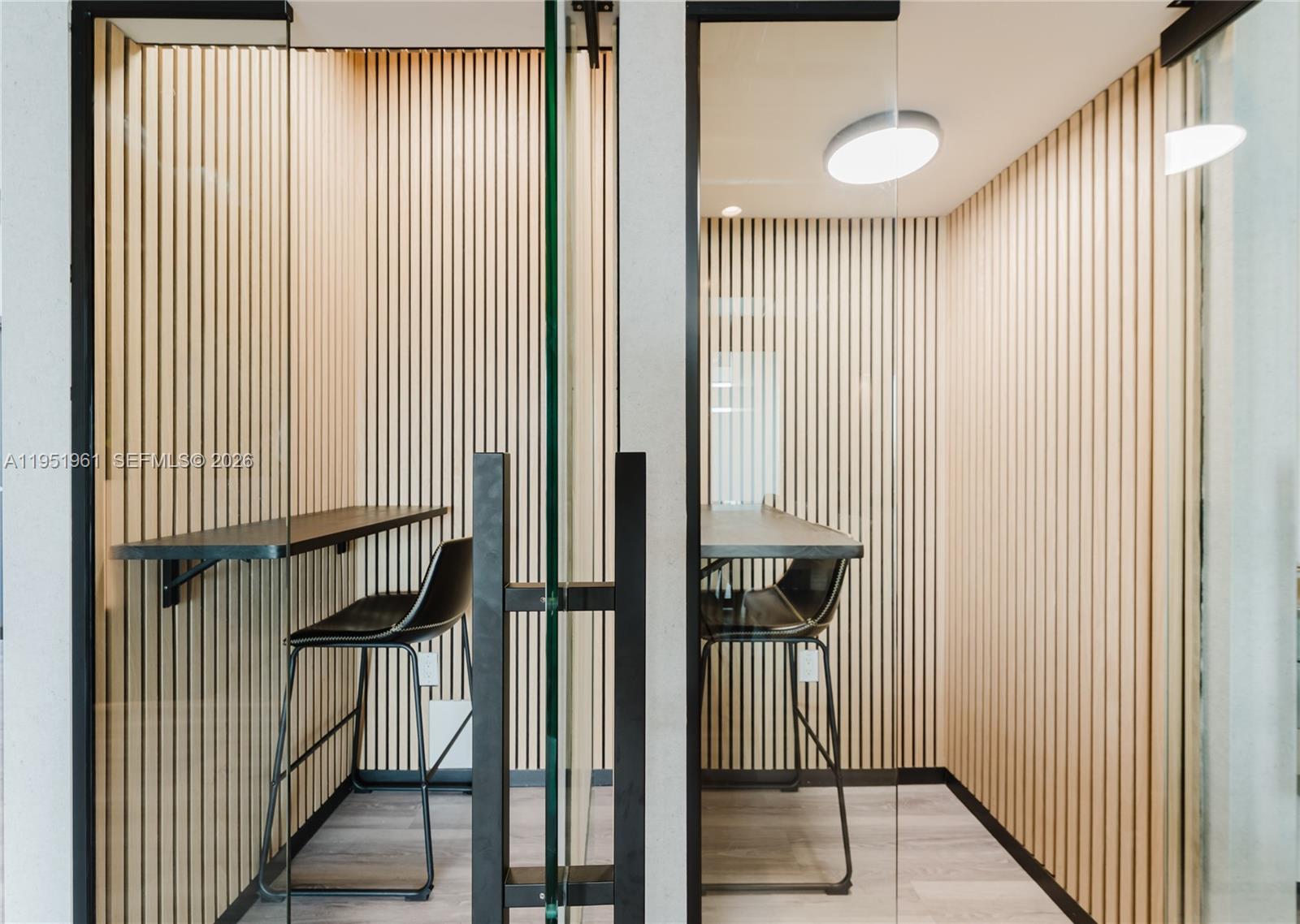 Two glass-enclosed office booths feature wood slat walls, black bar stools, and floating desks — 420 SW 7th St # 1017, Miami FL 33130, MIAMI, FL