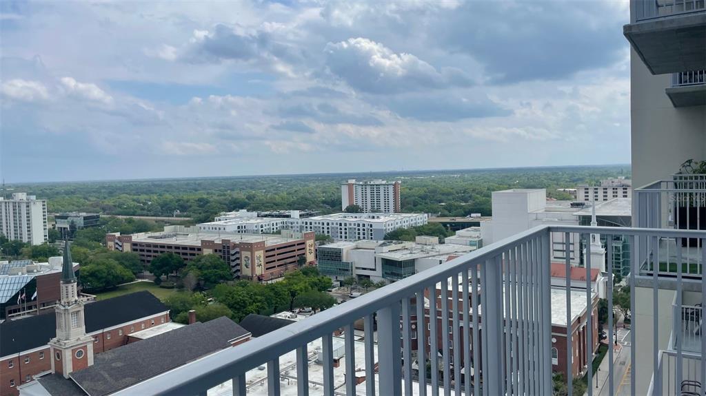 A high-angle view from a balcony overlooking a city skyline with buildings and trees — 155 S COURT AVENUE UNIT 1407, ORLANDO, FL