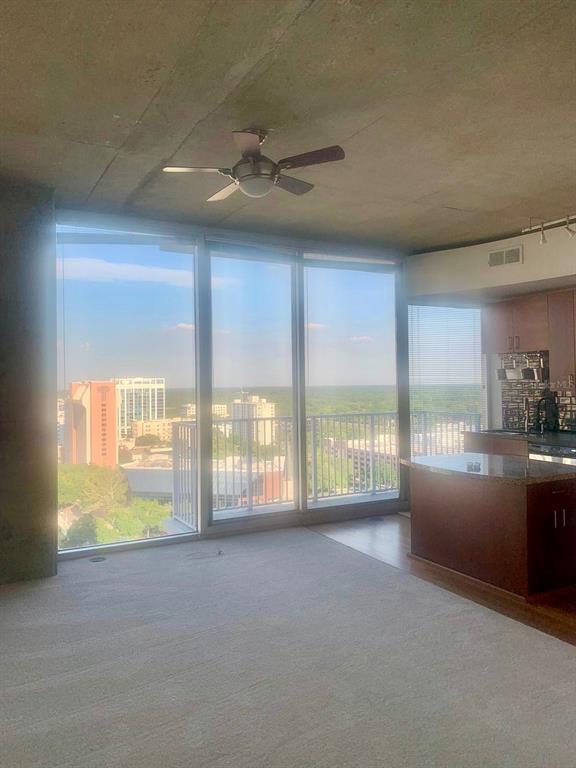A living area with wall-to-wall windows, a ceiling fan, and an adjacent kitchen island — 155 S COURT AVENUE UNIT 1407, ORLANDO, FL