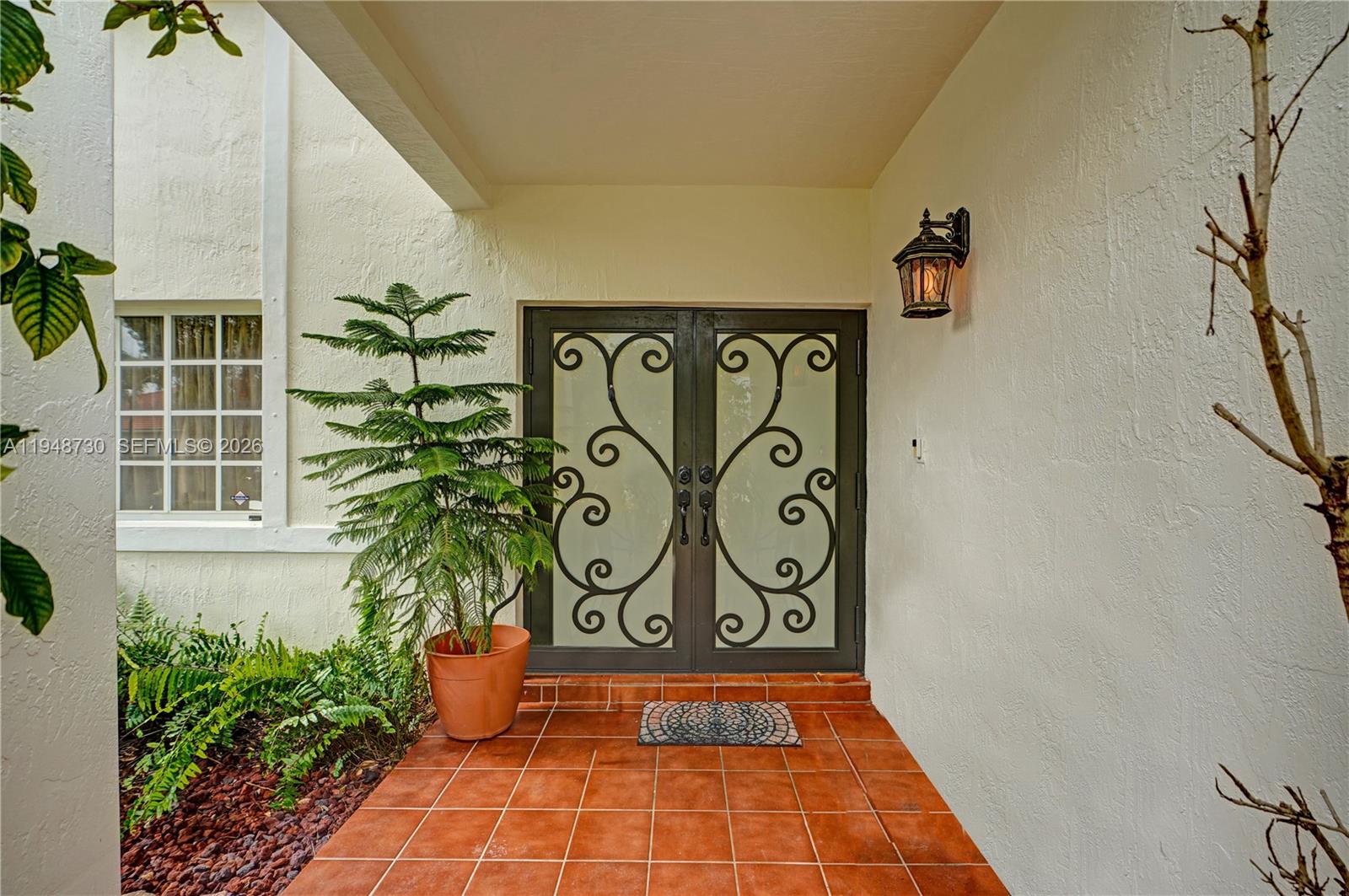 A covered entryway features a double glass door with iron scrollwork and terracotta floor tiles — 5502 SW 162nd Pl, Miami FL 33185, MIAMI, FL