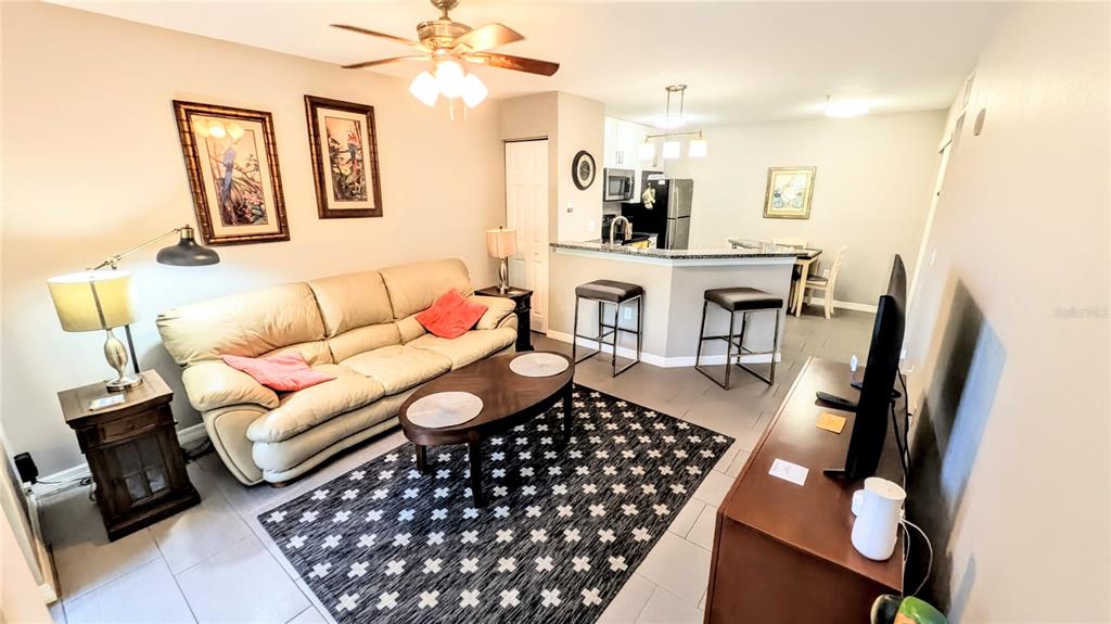 A living room features a beige sofa, a patterned rug, and an open kitchen area — 850 S TAMIAMI TRAIL UNIT 409, SARASOTA, FL