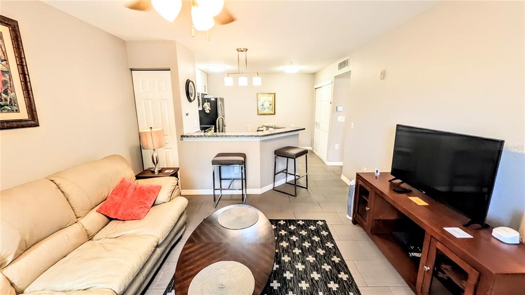 A living room with a beige sofa, television, and a kitchen breakfast bar — 850 S TAMIAMI TRAIL UNIT 409, SARASOTA, FL