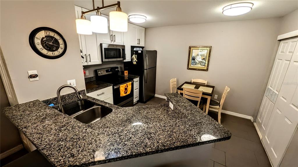 A kitchen features granite countertops, white cabinets, stainless steel appliances, and a small dining area — 850 S TAMIAMI TRAIL UNIT 409, SARASOTA, FL