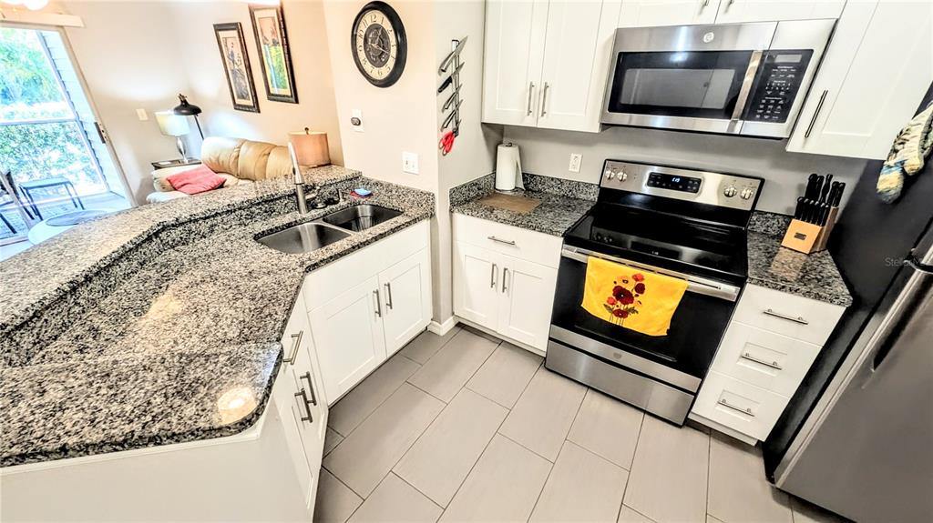 A kitchen features white cabinets, granite countertops, stainless steel appliances, and tile flooring — 850 S TAMIAMI TRAIL UNIT 409, SARASOTA, FL