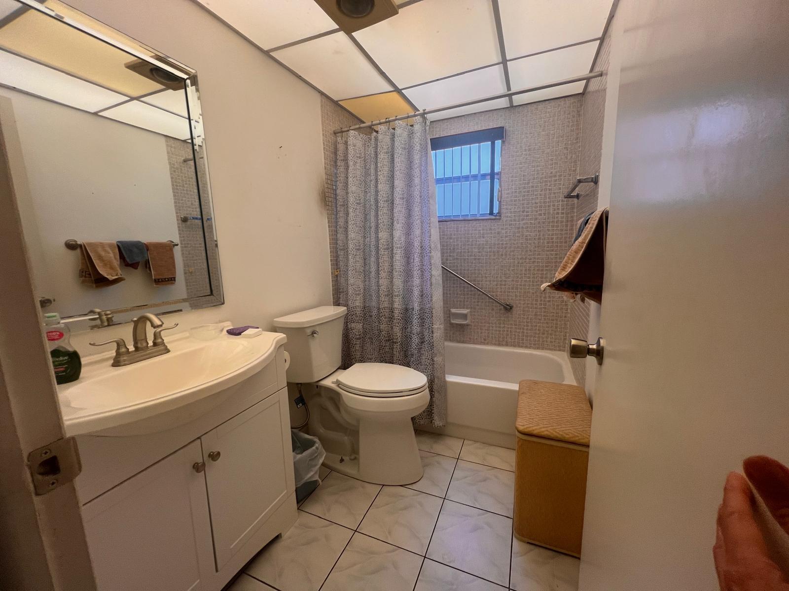 A bathroom with a vanity, toilet, and a tiled shower-tub combination under a drop ceiling — A Flanders # 5, Delray Beach FL 33484, DELRAY BEACH, FL
