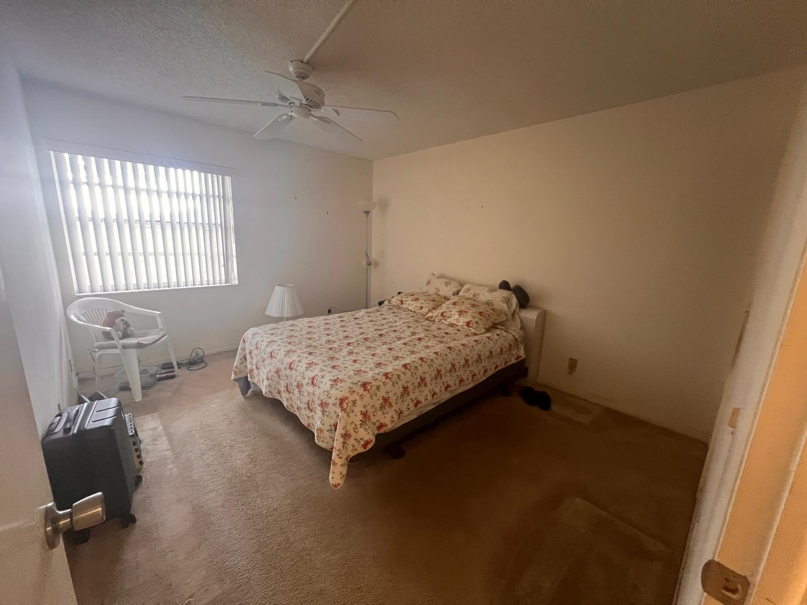 A bedroom with beige carpet, a floral bedspread, a ceiling fan, and vertical window blinds — A Flanders # 5, Delray Beach FL 33484, DELRAY BEACH, FL