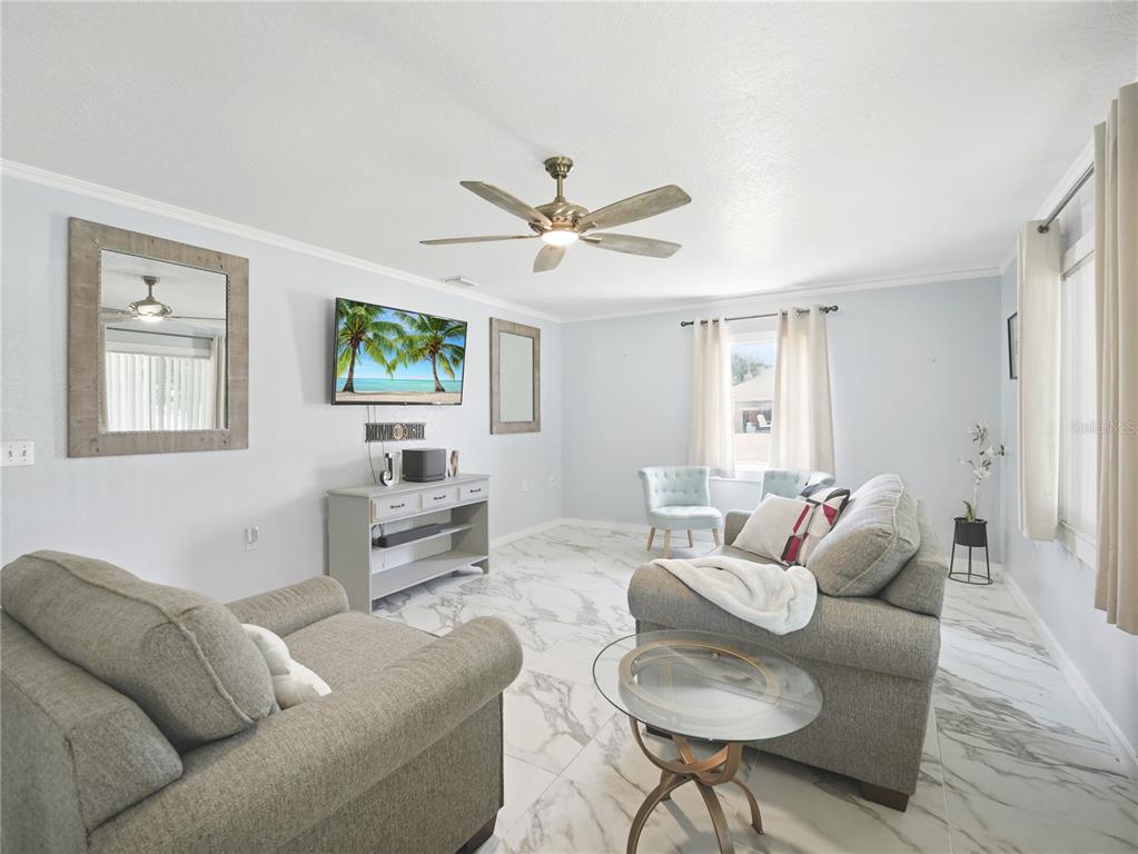 A living room features light gray walls, marble-look tile flooring, a ceiling fan, and furniture — 1423 LOUISIANA AVENUE, ST CLOUD, FL