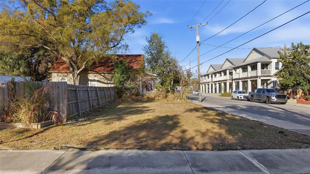 A vacant, grassy lot sits between a wooden fence and a street with multi-story buildings — 2616 N 19TH STREET, TAMPA, FL
