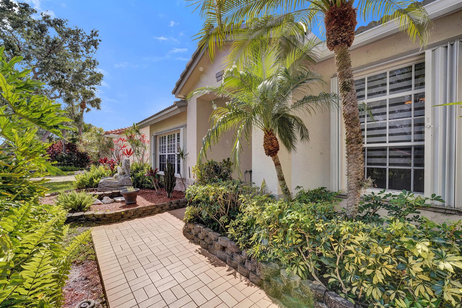 A paved walkway leads to the entrance of a house with a landscaped front yard — 3460 Dunes Vista Drive, Pompano Beach FL 33069, POMPANO BEACH, FL