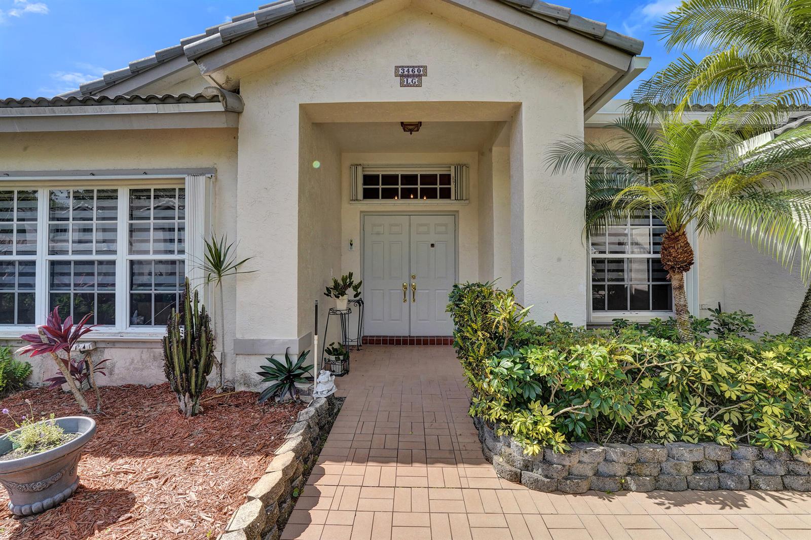 The exterior of a house features a paved walkway leading to double front doors — 3460 Dunes Vista Drive, Pompano Beach FL 33069, POMPANO BEACH, FL