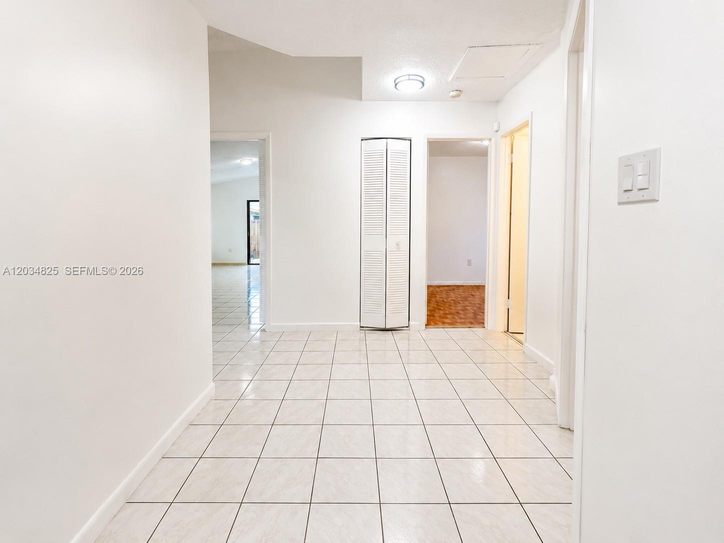 A tiled hallway features white walls, a bi-fold closet door, and two open doorways — 2485 W 70th Pl, Hialeah FL 33016, HIALEAH, FL