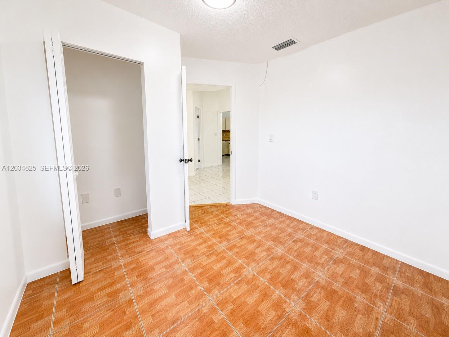 An empty room features white walls, a closet, and brown wood-look tile flooring — 2485 W 70th Pl, Hialeah FL 33016, HIALEAH, FL