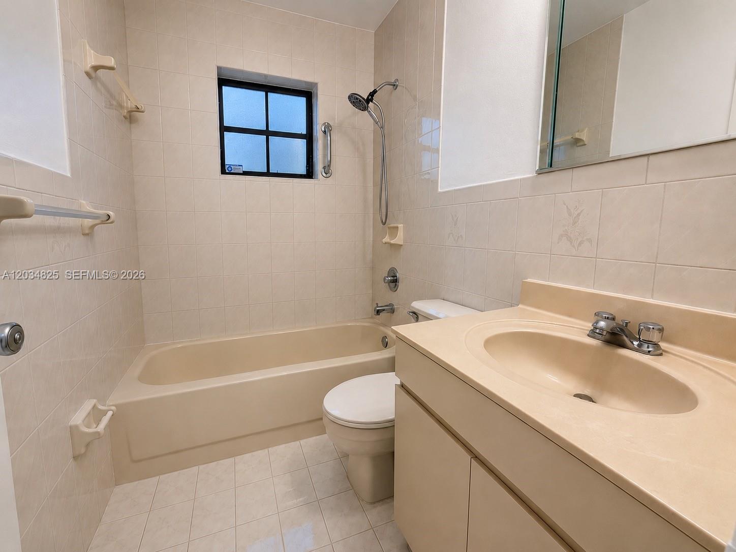 A bathroom features a beige tub, vanity, and toilet with light-colored wall and floor tiles — 2485 W 70th Pl, Hialeah FL 33016, HIALEAH, FL