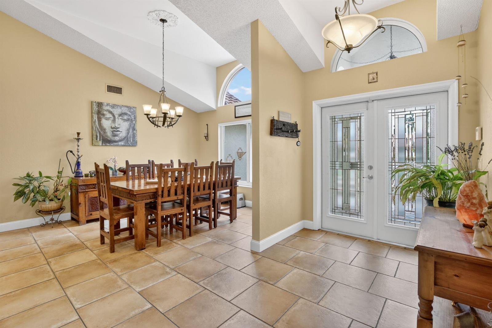 A dining area and entryway feature vaulted ceilings, tile flooring, and a double glass door — 11380 Wayne Drive, Cooper City FL 33026, COOPER CITY, FL