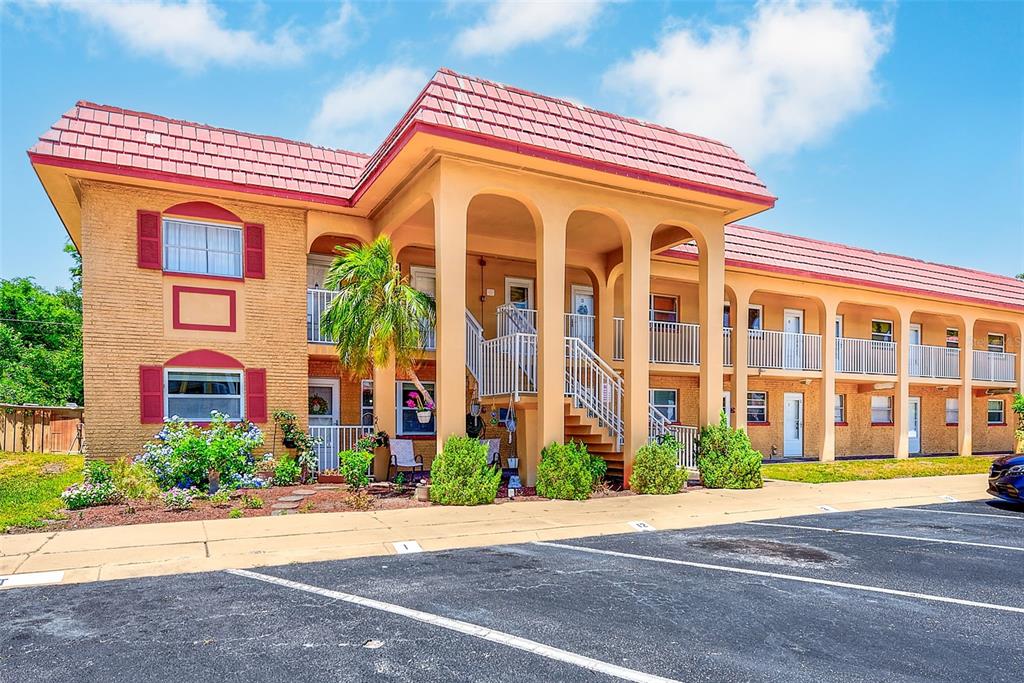 A two-story apartment building with a tan brick facade, red roof, and arched entryway — 1300 S HERCULES AVENUE UNIT 1, CLEARWATER, FL
